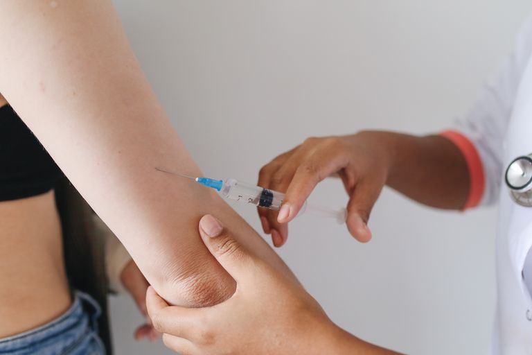 Doctor administering an injection to a patient's arm, close-up view.